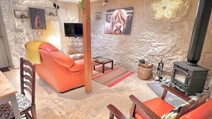 A cozy living room with a stone wall, a fireplace, and orange furniture. - Glamping Barn, High Pike, Caldbeck, Lake District (Caldbeck)