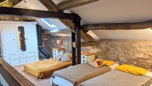 A bedroom with two beds, wooden beams, stone walls, and a skylight. - Glamping Barn, High Pike, Caldbeck, Lake District (Caldbeck)