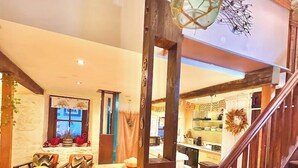A cozy living room with a wooden staircase, a dining area, and a kitchen visible through an open doorway. - Glamping Barn, High Pike, Caldbeck, Lake District (Caldbeck)