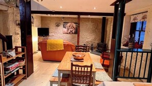 A cozy living room with a fireplace, a dining table, and a sofa. - Glamping Barn, High Pike, Caldbeck, Lake District (Caldbeck)