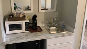 A compact kitchenette with a microwave, coffee maker, sink, and dishwasher. - Lakeside Motel (Ashland)