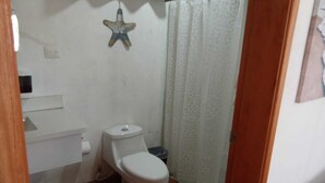 A small bathroom with a toilet, a sink, and a shower curtain. - Private Beach Villa w/ Pool • 5 Bedrooms • Sleeps 14 (El Velero)