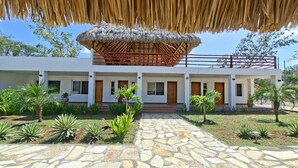 A modern building with a thatched roof structure, stone pathway, and tropical landscaping. - Private Beach Villa w/ Pool • 5 Bedrooms • Sleeps 14 (El Velero)
