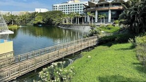 Un hotel moderno con una fuente de agua, un puente y abundante vegetación.