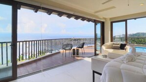 Un balcón espacioso con vistas al mar, un sofá blanco y un ventilador de techo.
