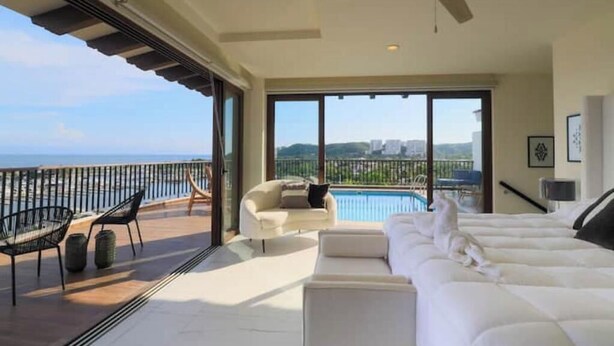 Un balcón amplio con piscina, un sofá blanco y una silla.