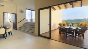 Un interior moderno con comedor, escalera y balcón con vistas a la ciudad.