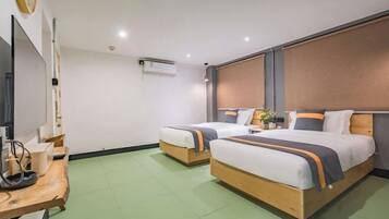 A hotel room with two beds, a wooden desk, a flat-screen TV, and a large window.