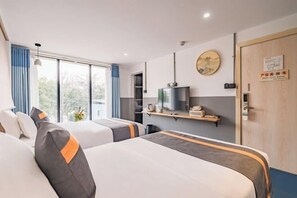 A hotel room with two beds, a television, a shelf with items, and a door with a sign. - Xihu Yingxiu Xinsu Guesthouse (Huizhou)