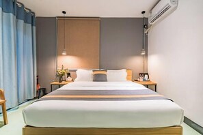 A hotel room with a large bed, two bedside tables, a nightstand, a lamp, and an air conditioning unit. - Xihu Yingxiu Xinsu Guesthouse (Huizhou)