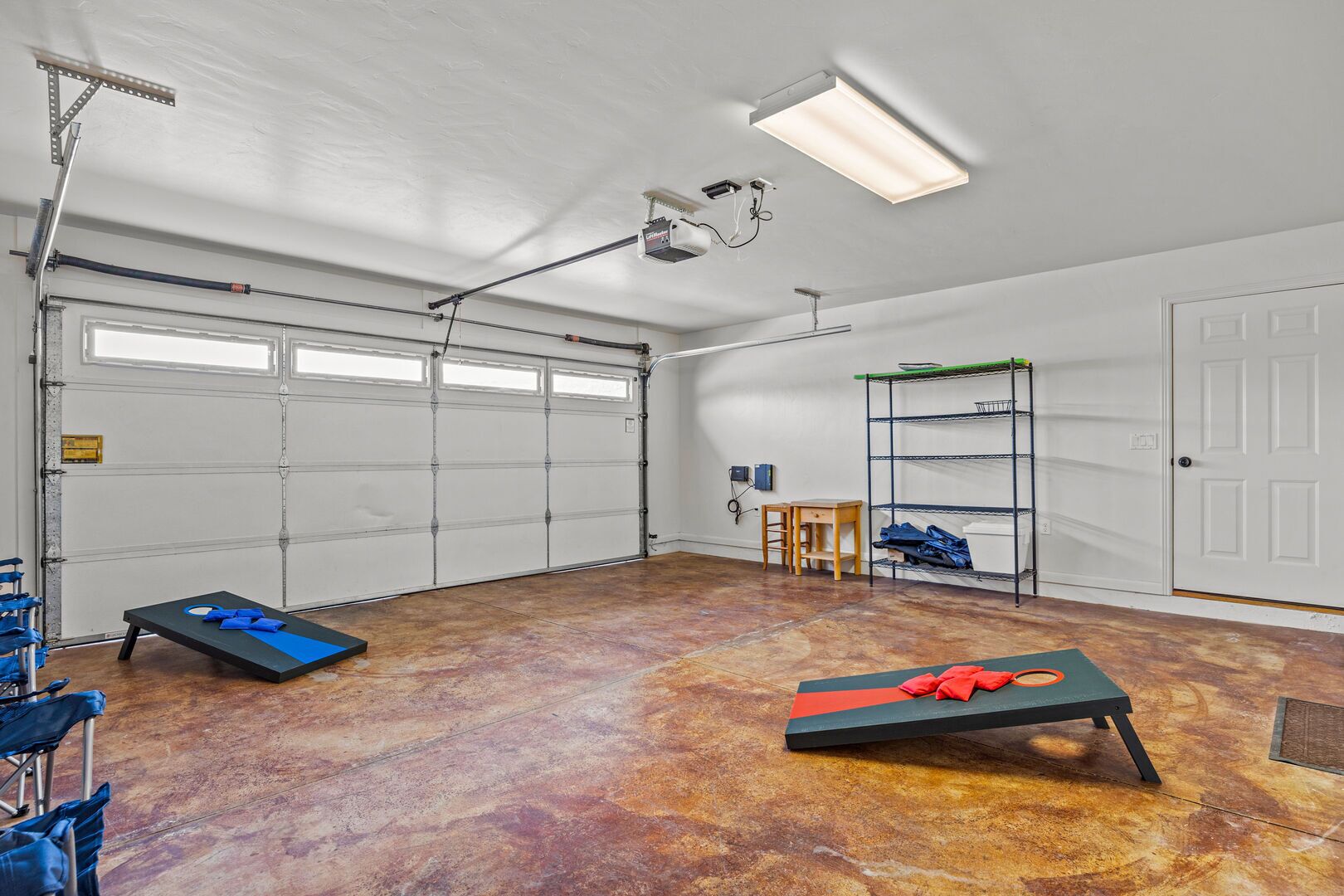 A spacious garage with a concrete floor, a ceiling-mounted light, and a metal shelving unit.
