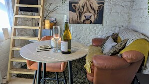 Una habitación acogedora con una mesa redonda, una botella de vino, dos copas, una vela y un cuadro de un león en la pared.