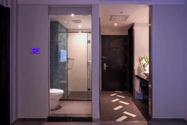 A modern bathroom with a glass-enclosed shower, a visible toilet, and a herringbone-patterned floor. - Orange Hotel (Hefei Sanxiaokou Subway Station Store) (Hefei)