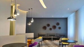 Una moderna area lounge con disposizione dei posti a sedere, illuminazione a sospensione e decorazioni alle pareti.