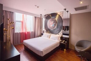 A hotel room with a large bed, a desk, a chair, a mirror, and a record player. - Orange Hotel (Hefei Sanxiaokou Subway Station Store) (Hefei)