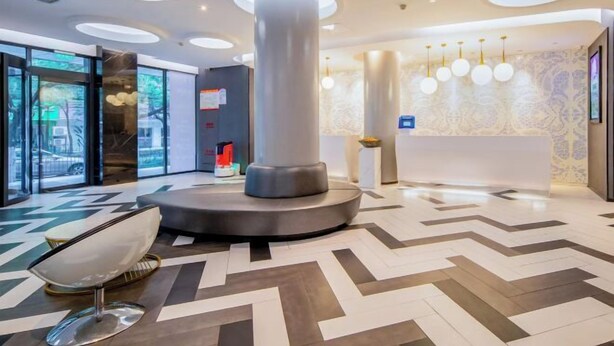 Una hall moderna con una colonna centrale, una scrivania della reception e un pavimento decorato.