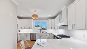 Una cocina moderna con armarios blancos, una isla central y un amplio ventanal con vistas.