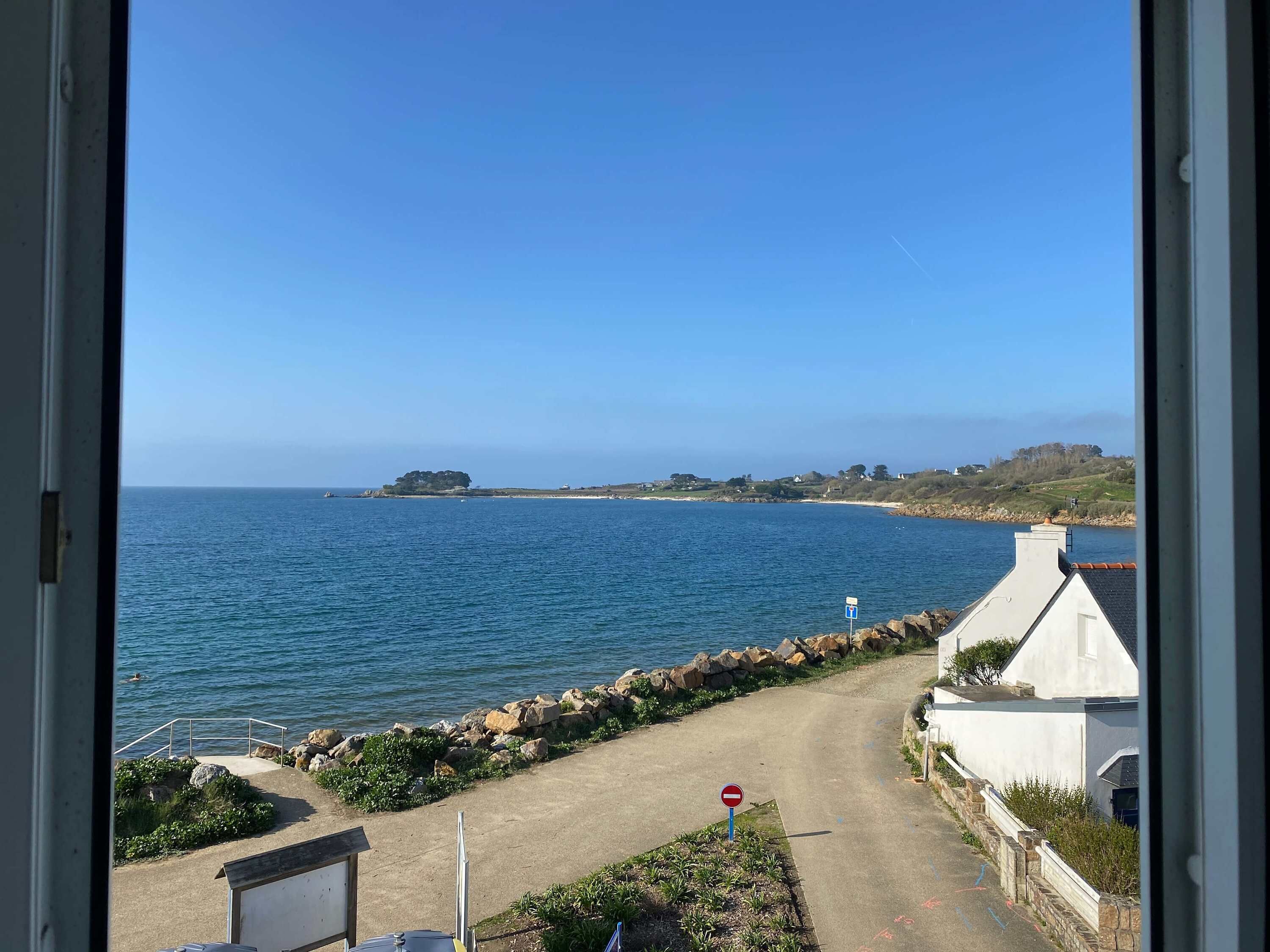 Une vue sur la côte, avec un ciel dégagé, une rive rocheuse et un panneau indiquant l’interdiction d’accès.