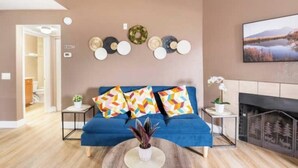 A modern living room with a blue sofa, decorative wall art, and a fireplace. - Affordable & Convenient Condo Near Vegas Strip (Las Vegas)