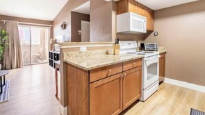 A modern kitchen with wooden cabinets, a built-in microwave, and a stove. - Affordable & Convenient Condo Near Vegas Strip (Las Vegas)