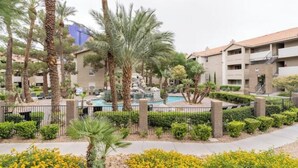 A hotel courtyard with palm trees, a swimming pool, and a landscaped garden. - Affordable & Convenient Condo Near Vegas Strip (Las Vegas)