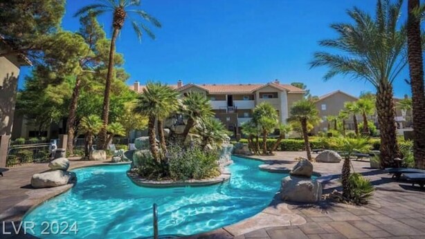 A resort pool area with palm trees, a water feature, and buildings in the background. - Affordable & Convenient Condo Near Vegas Strip (Las Vegas)
