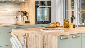 A modern kitchen with a wooden island, stainless steel appliances, and a view of the city.