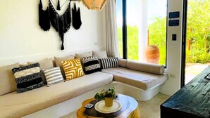 Una sala de estar moderna con un sofá blanco, una mesa de centro de madera y una lámpara colgante.