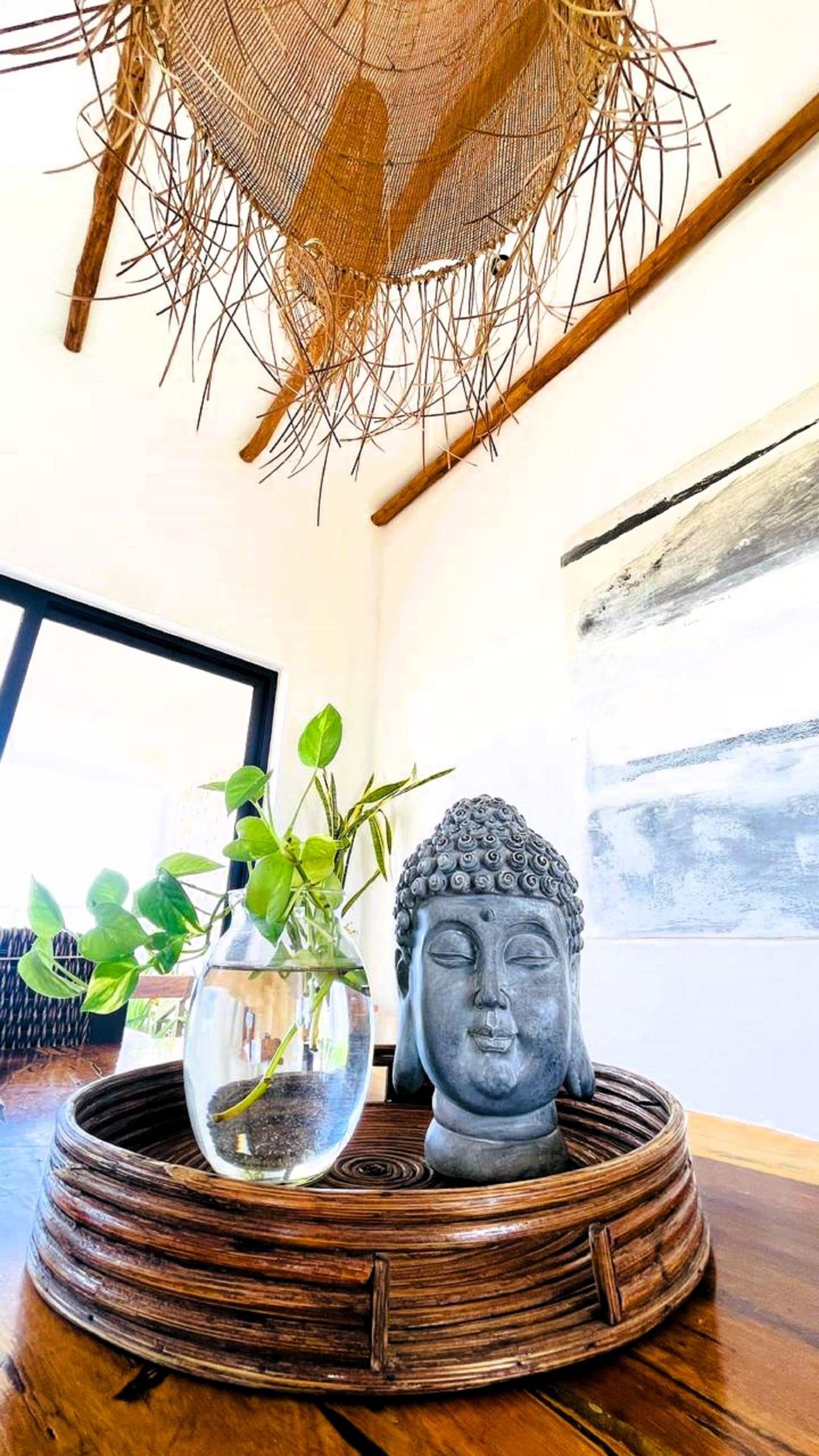 Ein Zimmer mit einem gewebten Korb, der eine Buddha-Statue und eine Topfpflanze enthält.