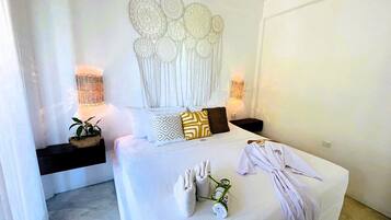 A modern bedroom with a large bed, decorative wall art, bedside lamps, and a potted plant.