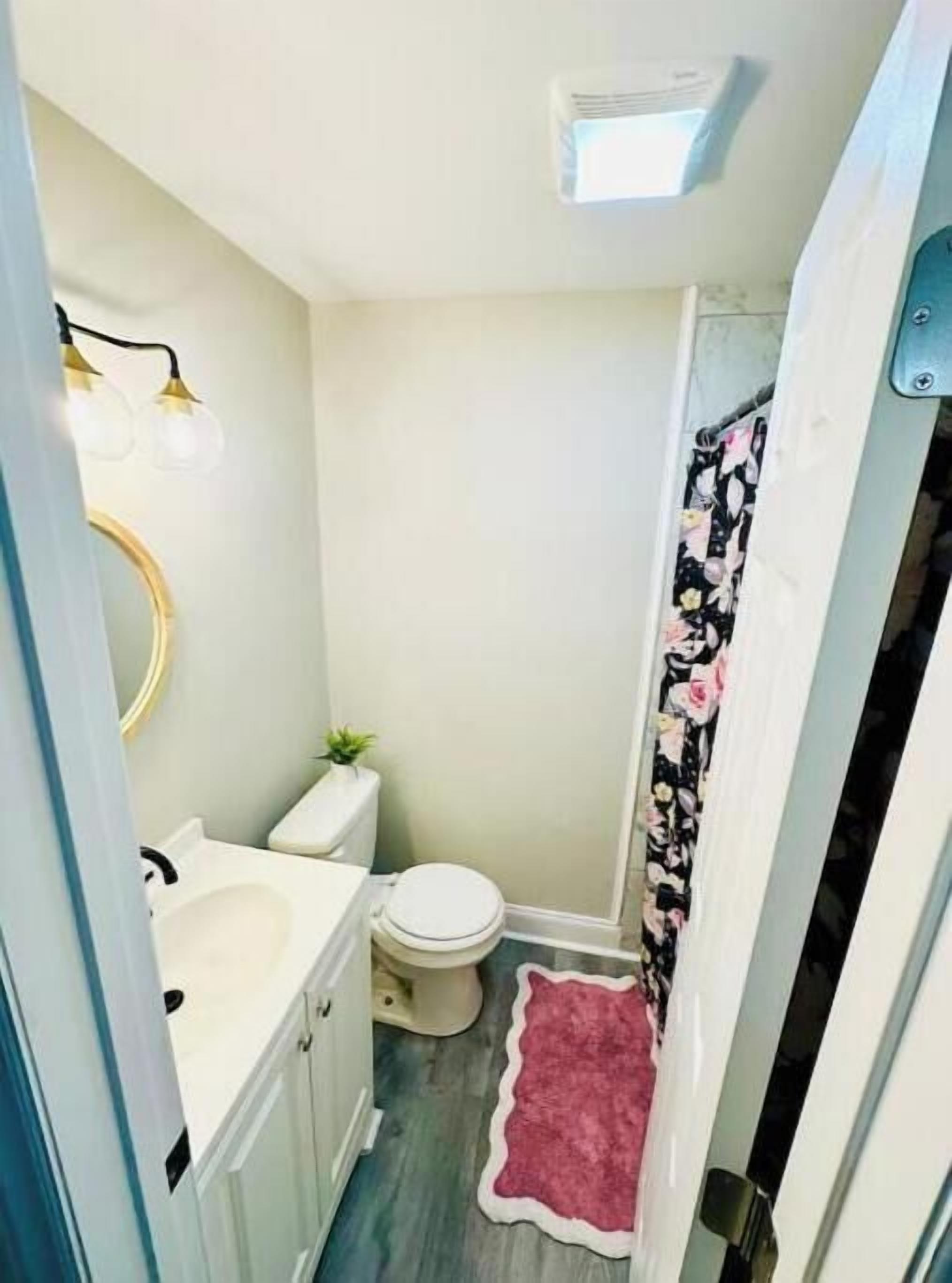 A compact bathroom with a toilet, sink, and shower.