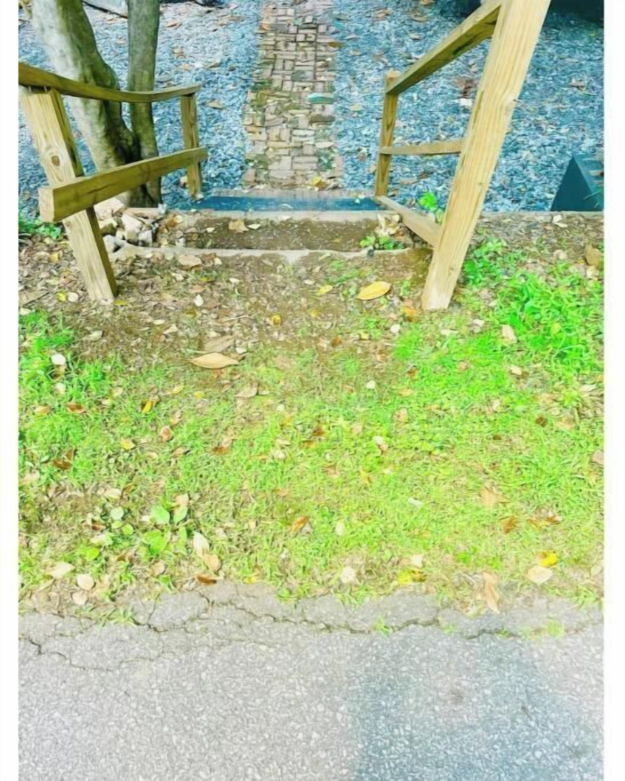 A wooden staircase leading up to a stone pathway.
