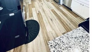 A modern kitchen with stainless steel appliances, a dining area with a table and chairs, and a wooden floor. - 2BR Swamp Rabbit Getaway (Greenville)