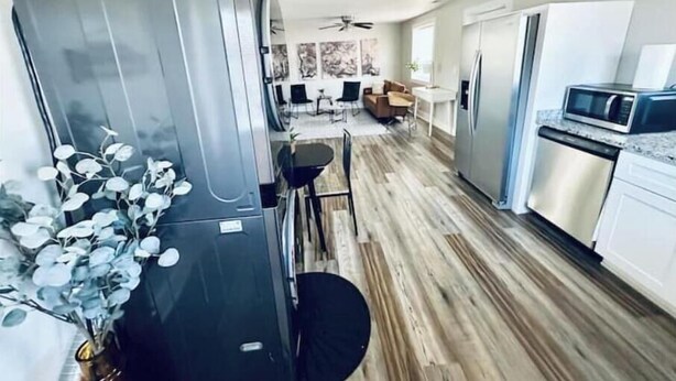 A modern kitchen with stainless steel appliances, a dining area with a black table and chairs, and a living area with a sofa and coffee table. - 2BR Swamp Rabbit Getaway (Greenville)