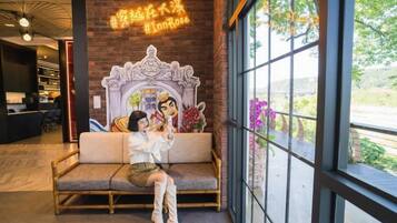 A seating area with a mural, a large window, and a view of greenery.