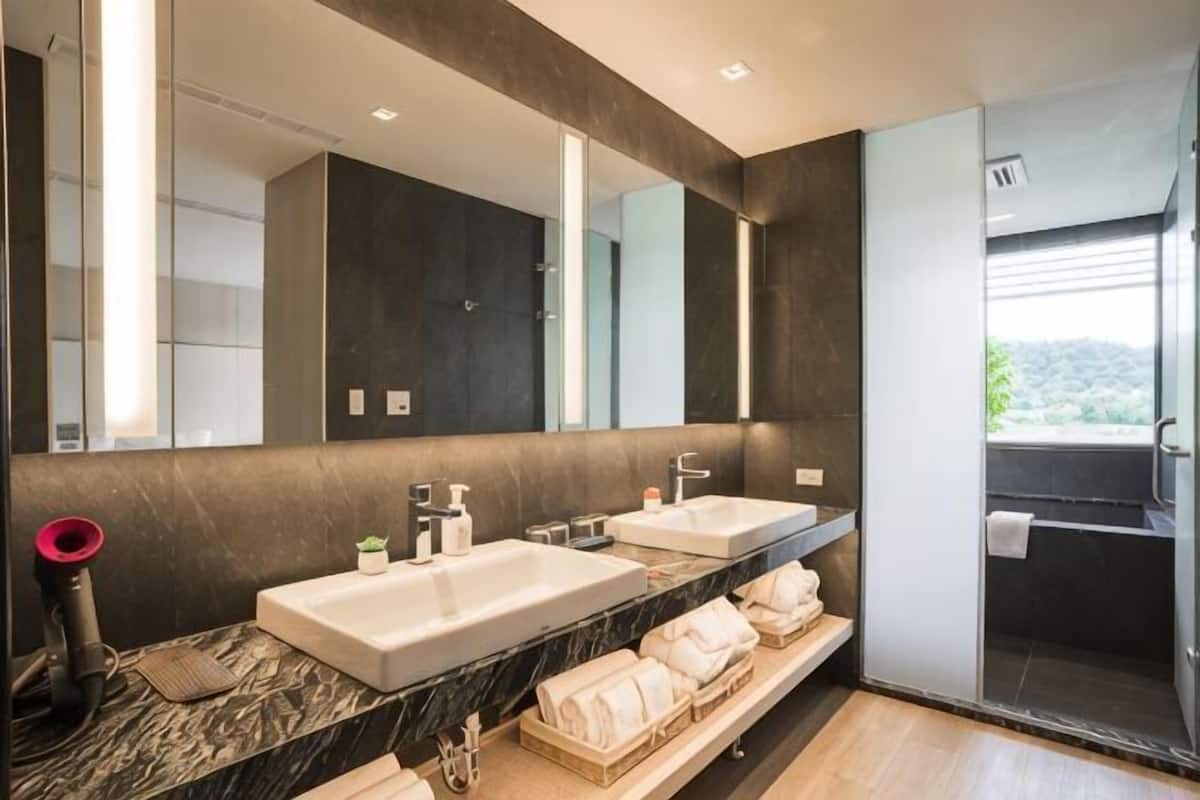 Ein modernes Badezimmer mit zwei Waschbecken, einem großen Spiegel und einer Duschkabine.