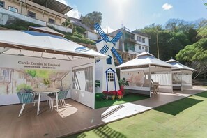 An outdoor event space with tents, a windmill, and a table with chairs.