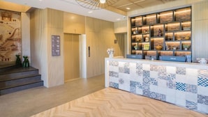 A reception area with a patterned counter, a modern chandelier, and a display of decorative items. - Inn Rose (Taoyuan)