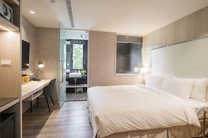 A modern hotel room with a large bed, a desk, and a bathroom visible through a glass door. - Inn Rose (Taoyuan)