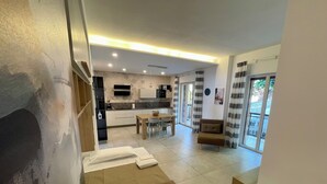 Una sala de estar moderna con un sofá, un comedor y una cocina al fondo.