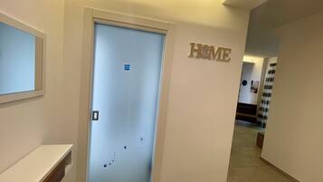 Ein Flur mit einer Tür, auf der „HOME“ steht, einem kleinen Regal und einem an der Wand befestigten Schild.