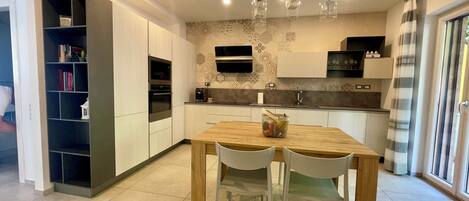 Una cocina moderna con una mesa de comedor de madera, sillas blancas y una estantería empotrada.