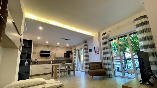 Una sala moderna con un sofá, un televisor y una zona de comedor con una mesa y sillas.