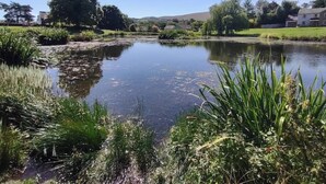 A calm river with surrounding greenery and houses in the background. - Glamping Barns & Bothy, in Caldbeck, Lake District (Caldbeck)