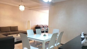 Ein modernes Wohnzimmer mit Essbereich, einer Couch, einem Couchtisch und einer Chandelier.