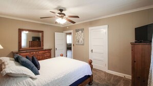 A bedroom with a bed, dresser, mirror, ceiling fan, and a television. - Miss Audrey’s House is a charming cottage in the heart of historic Richmond Hill (Richmond Hill)