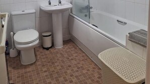 Casa de banho com sanita, lavatório e chuveiro.