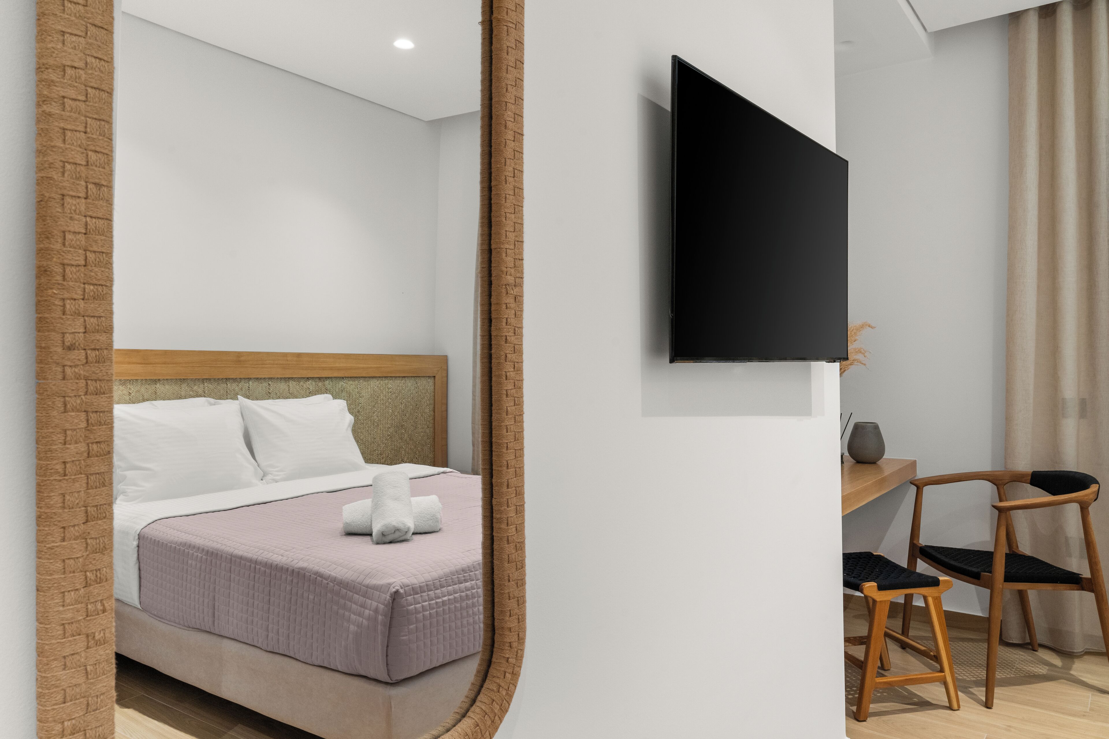 Un dormitorio moderno con una cama, un televisor montado en la pared, un escritorio con una silla y una pared decorativa de ladrillo.