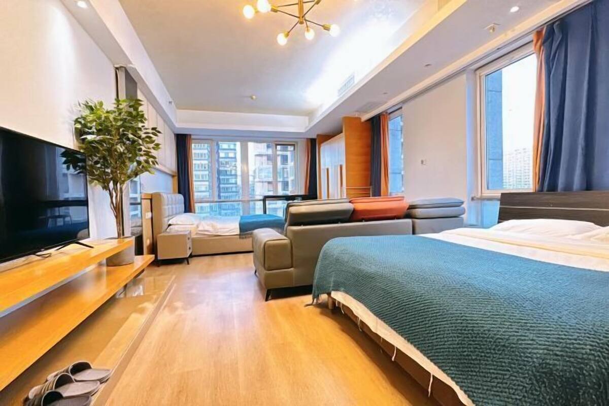 Una camera d'albergo moderna con un letto grande, una televisione, un divano e una pianta.