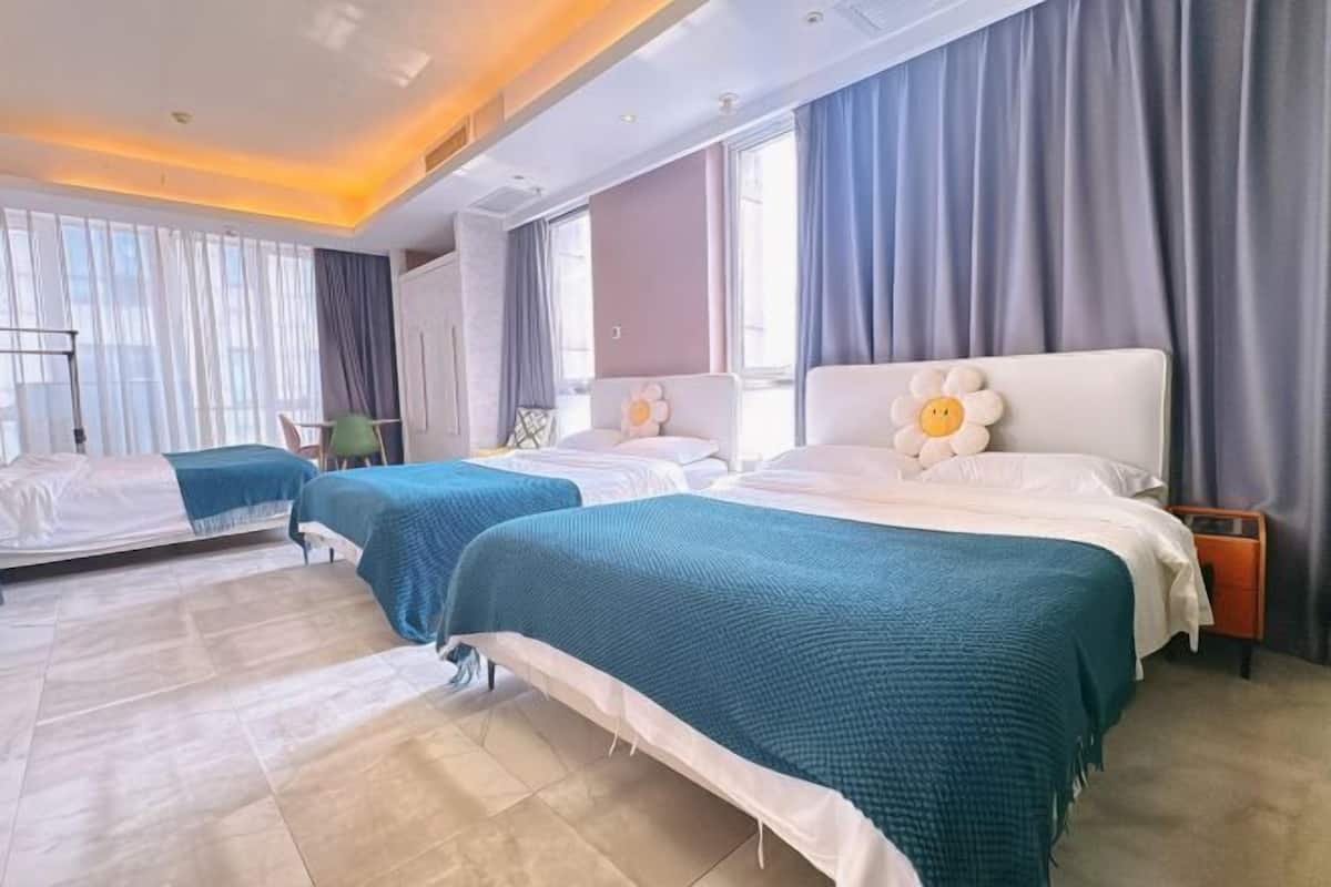 Una camera d'albergo con due letti, una grande finestra e un comodino con una lampada.